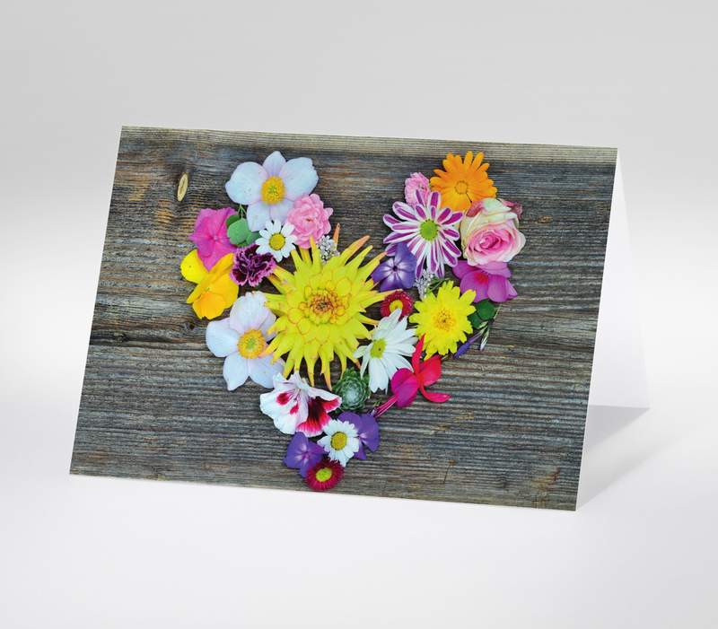 Blumenherz aus bunten Sommerblumen auf rustikalem Holzuntergrund