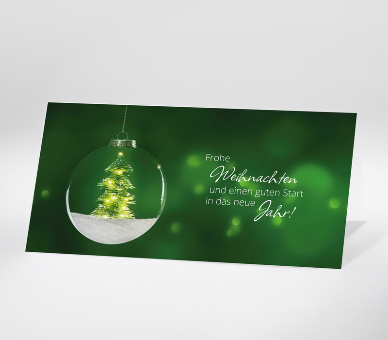Minimalistische Weihnachtskarte mit gläserner Christbaumkugel und leuchtendem Weihnachtsbaum, grüner Hintergrund, Text: Frohe Weihnachten und einen guten Start in das neue Jahr