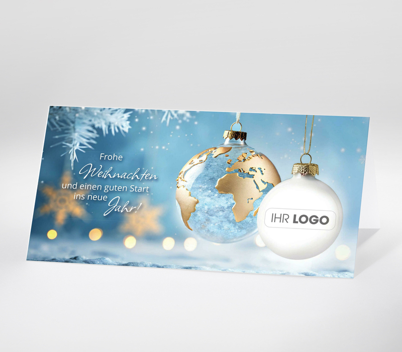 Weihnachtskugel mit Weltkarte und Text Frohe Weihnachten vor winterlichem Hintergrund