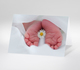 Babykarte mit kleinen Füßen und Gänseblümchen auf weißem Hintergrund  
