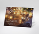 Weihnachtskarte mit Lichterkette, Holzsternen und Weihnachtskugeln auf Holztisch
