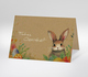 Osterkarte mit Osterhase und bunten Eiern auf Kraftpapier-Hintergrund, Text Frohes Osterfest.